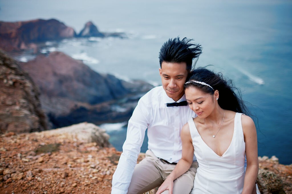 Brautpaar mit aneinandergelegten Köpfen auf den Klippen der Algarve über einem Strand in Portugal