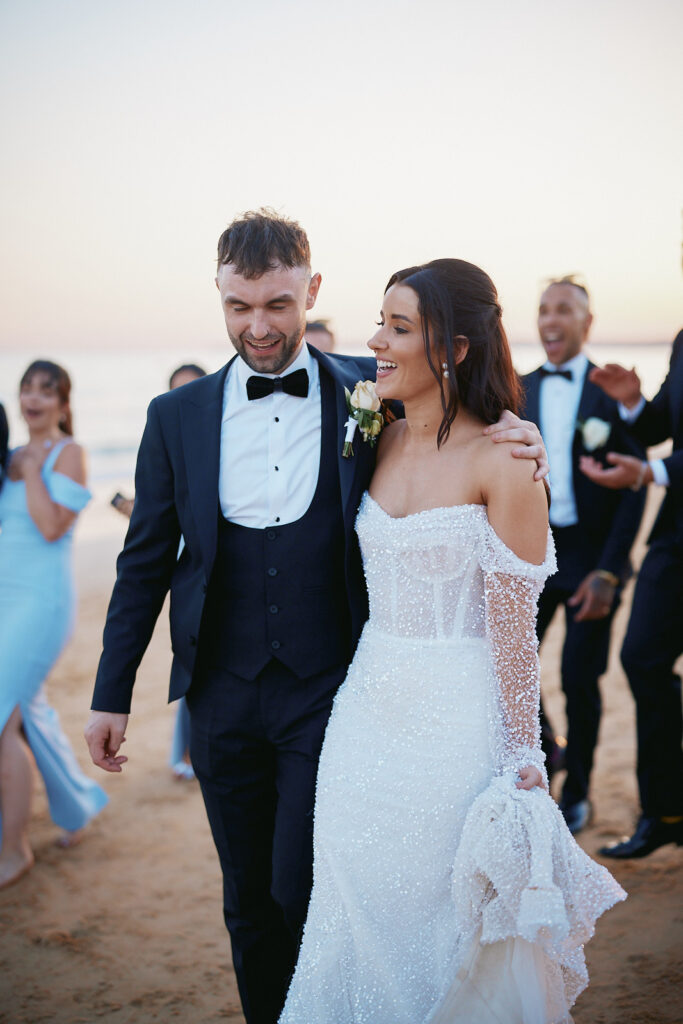 Brautpaar geht am Strand bei der Hochzeitsfeier im Vidamar Resort Algarve gemeinsam entlang