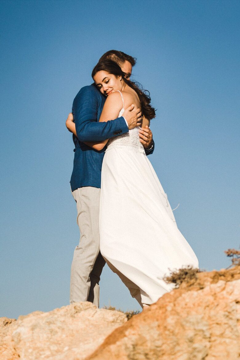 Couple embracing on dramatic cliffs during their Algarve elopement in Portugal