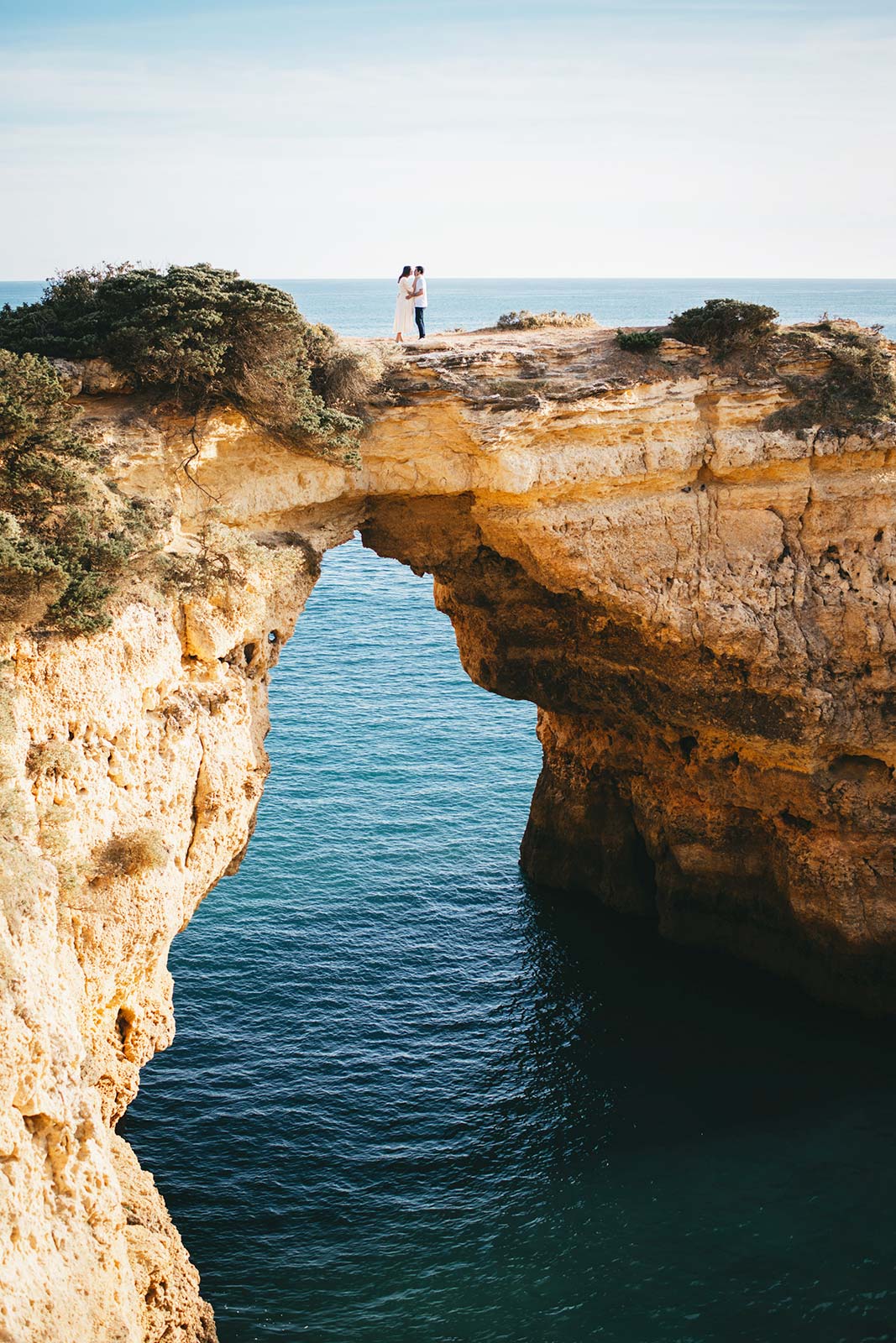 Couple standing on dramatic Algarve cliffs above the Atlantic Ocean during an intimate elopement in Portugal