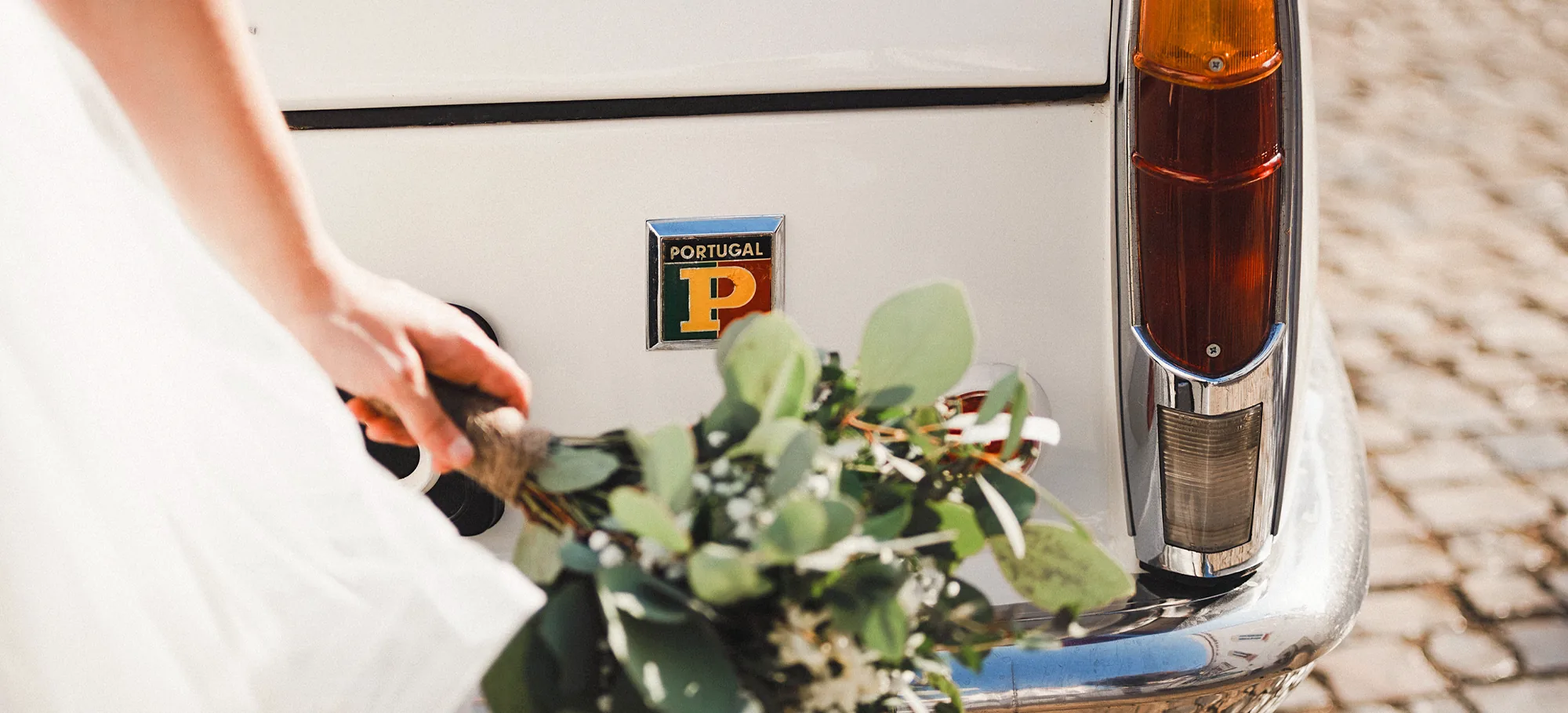 Bride holding bouquet beside vintage Portuguese car during intimate Portugal elopement