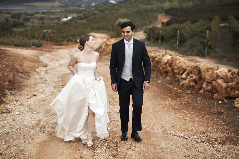 Braut und Bräutigam gehen für ihre Paarfotos über einen Weg durch die Weinberge des Weinguts Arvad an der Algarve