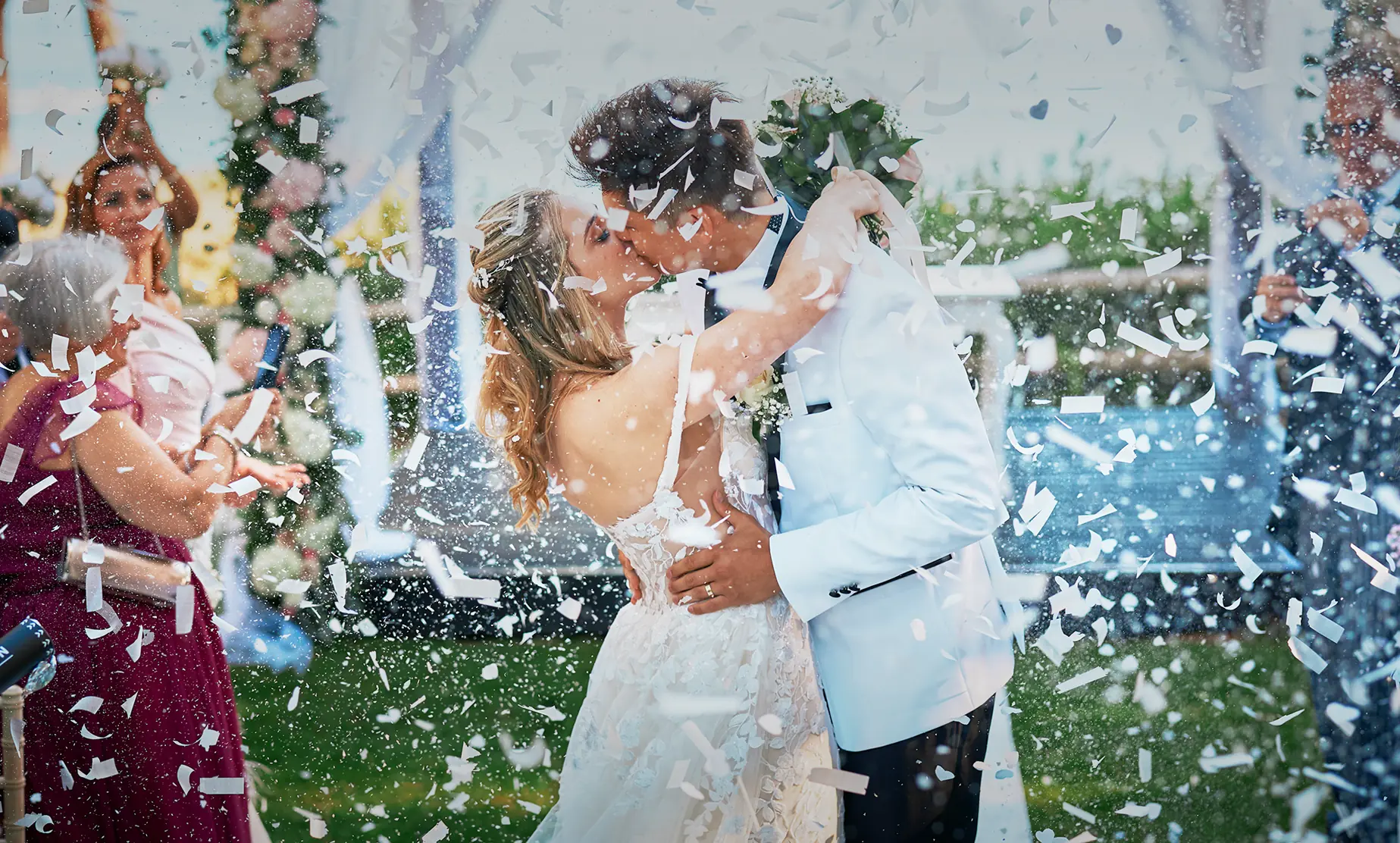 Bride and groom kissing under confetti after their wedding ceremony in the Algarve, Portugal