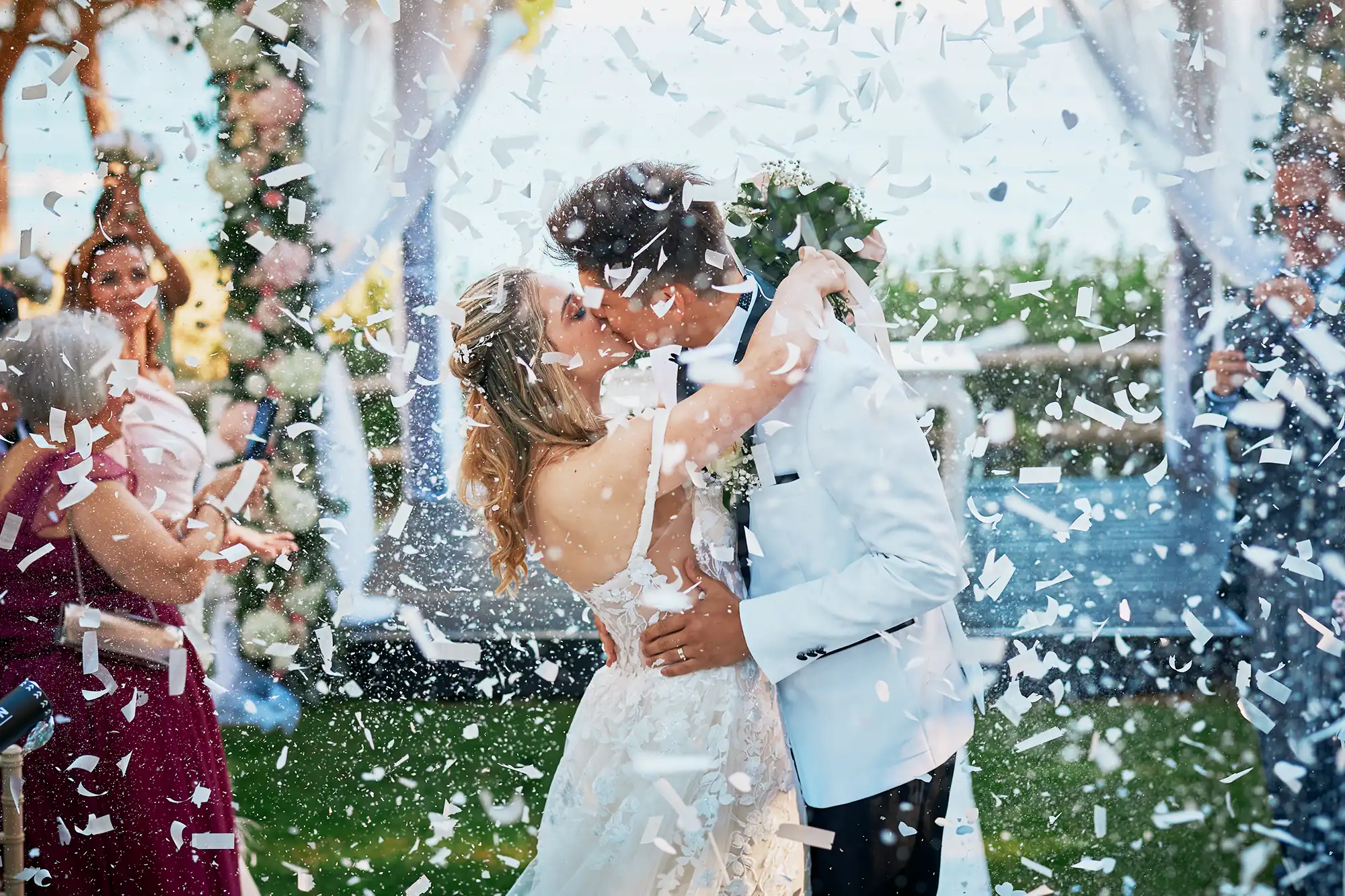 Bride and groom kissing under confetti after their wedding ceremony in the Algarve, Portugal