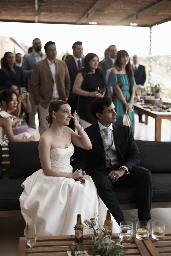 Braut und Bräutigam sitzen während einer emotionalen Rede bei ihrer Hochzeitsfeier im Arvad in der Algarve