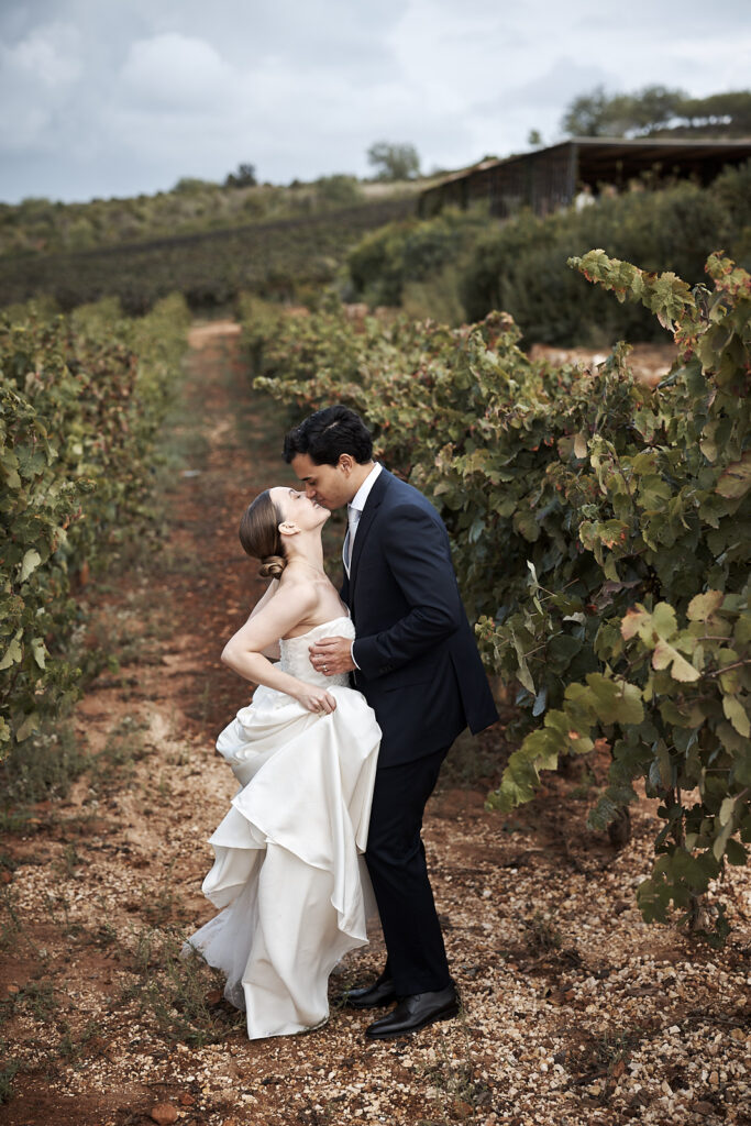 Braut und Bräutigam küssen sich im Weinberg des Weinguts Arvad in der Algarve