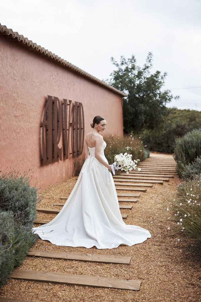 Braut mit Brautstrauss auf dem Weg vor dem Weingut Arvad in der Algarve