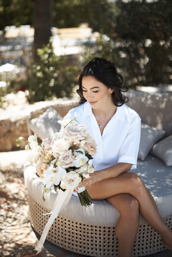Braut sitzt mit ihrem Brautstrauß während der Vorbereitungen im Monte do Serrinho an der Algarve, Portugal