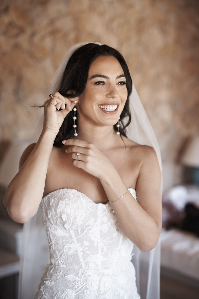 Schwarz-Weiß-Porträt der Braut beim Anlegen ihrer Perlenohrringe im Monte do Serrinho an der Algarve, Portugal