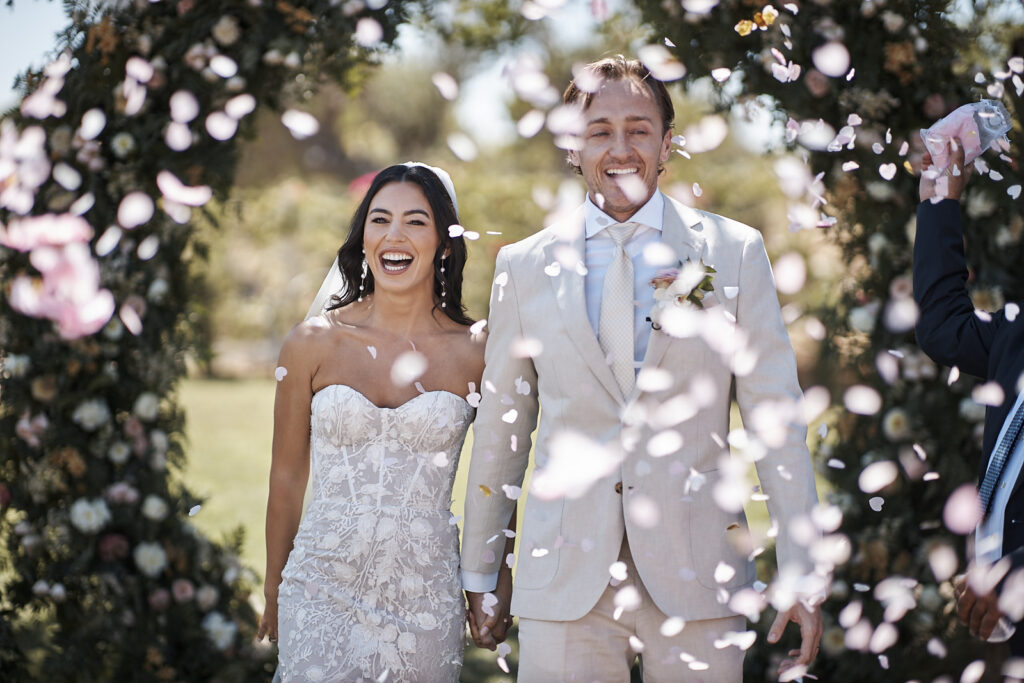 Braut und Bräutigam laufen nach der freien Trauung durch Blütenblätter bei ihrer Monte do Serrinho Hochzeit an der Algarve