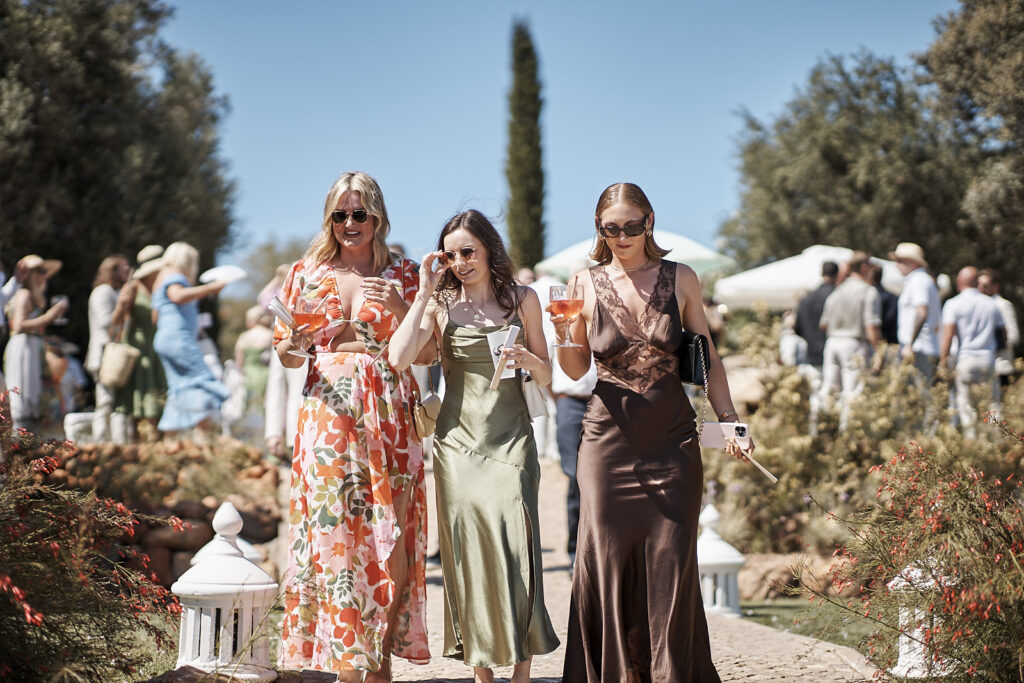 Hochzeitsgäste mit Getränken gehen über einen Gartenweg bei der Monte do Serrinho Hochzeit an der Algarve