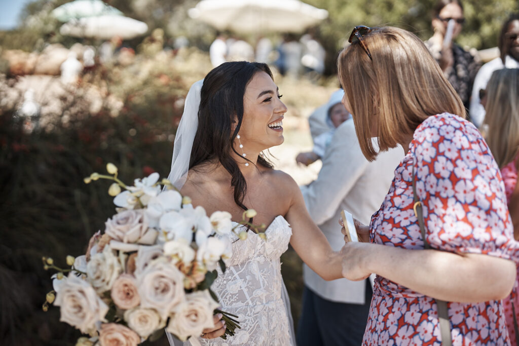 Braut mit Brautstrauß unterhält sich nach der Trauung mit einem Hochzeitsgast im Monte do Serrinho an der Algarve