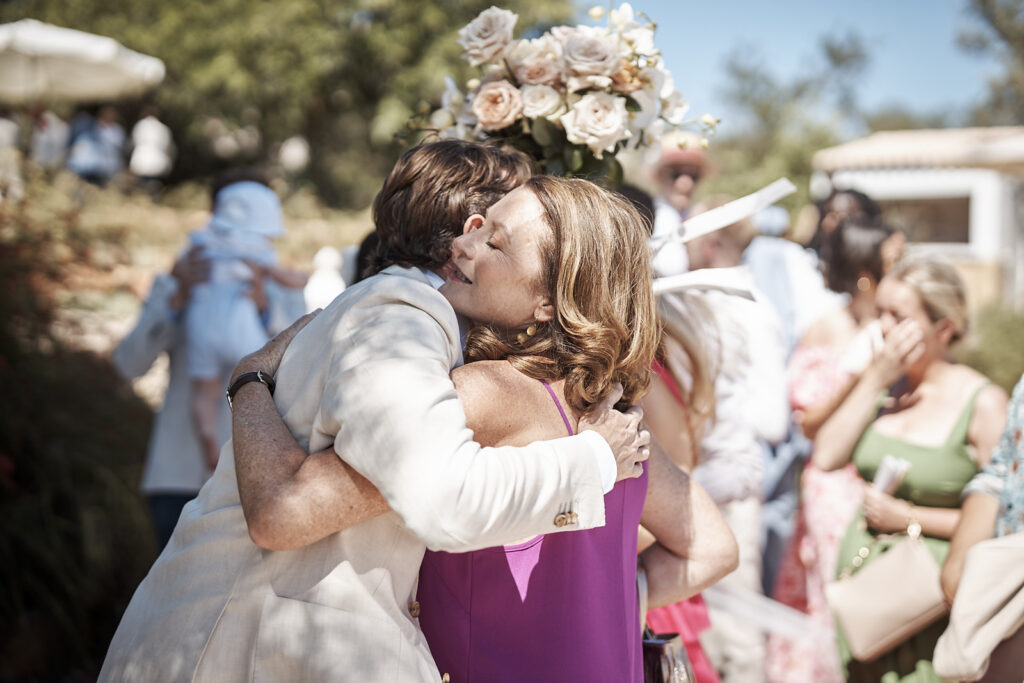 Bräutigam umarmt einen Hochzeitsgast nach der Trauung im Garten von Monte do Serrinho an der Algarve