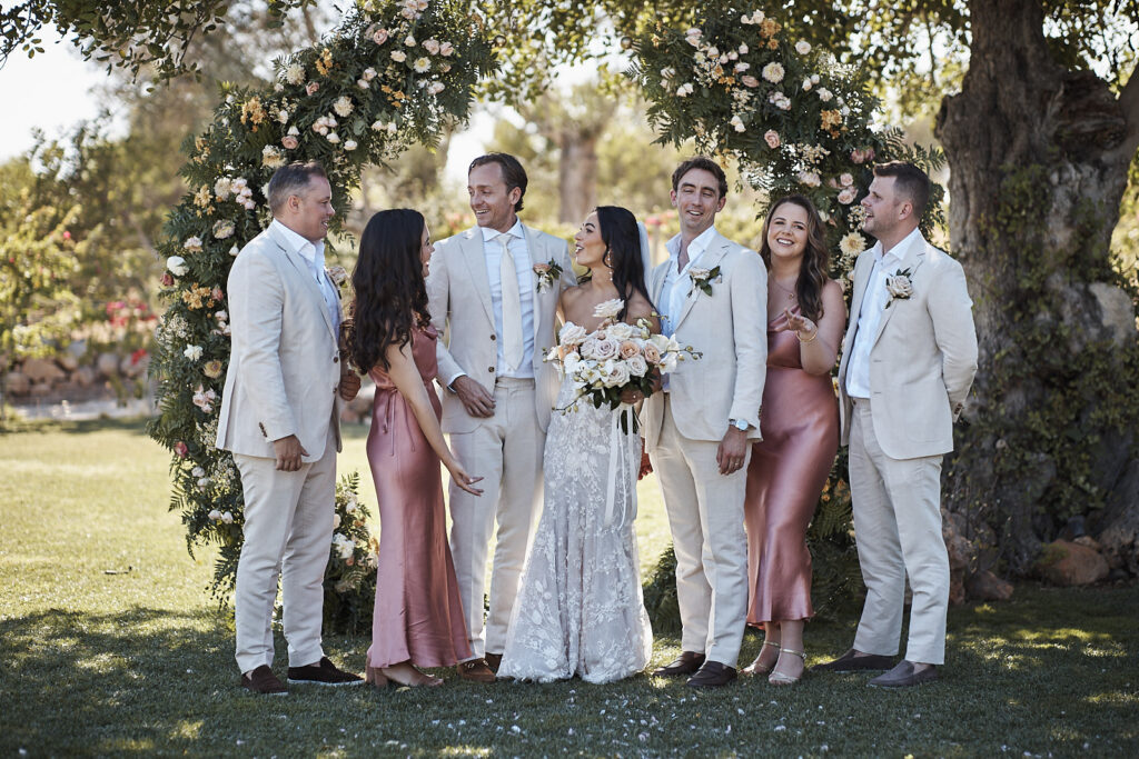 Brautpaar mit Brautjungfern und Groomsmen unter dem Blumenbogen nach der Trauung im Monte do Serrinho an der Algarve