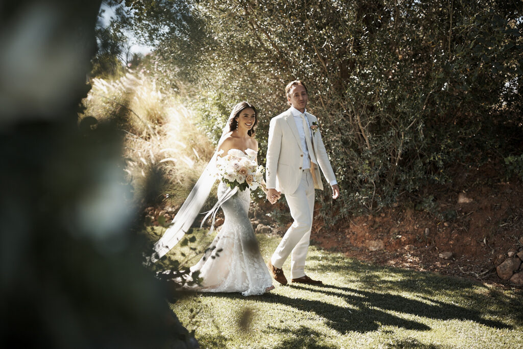 Braut und Bräutigam gehen Hand in Hand durch den Garten von Monte do Serrinho an der Algarve