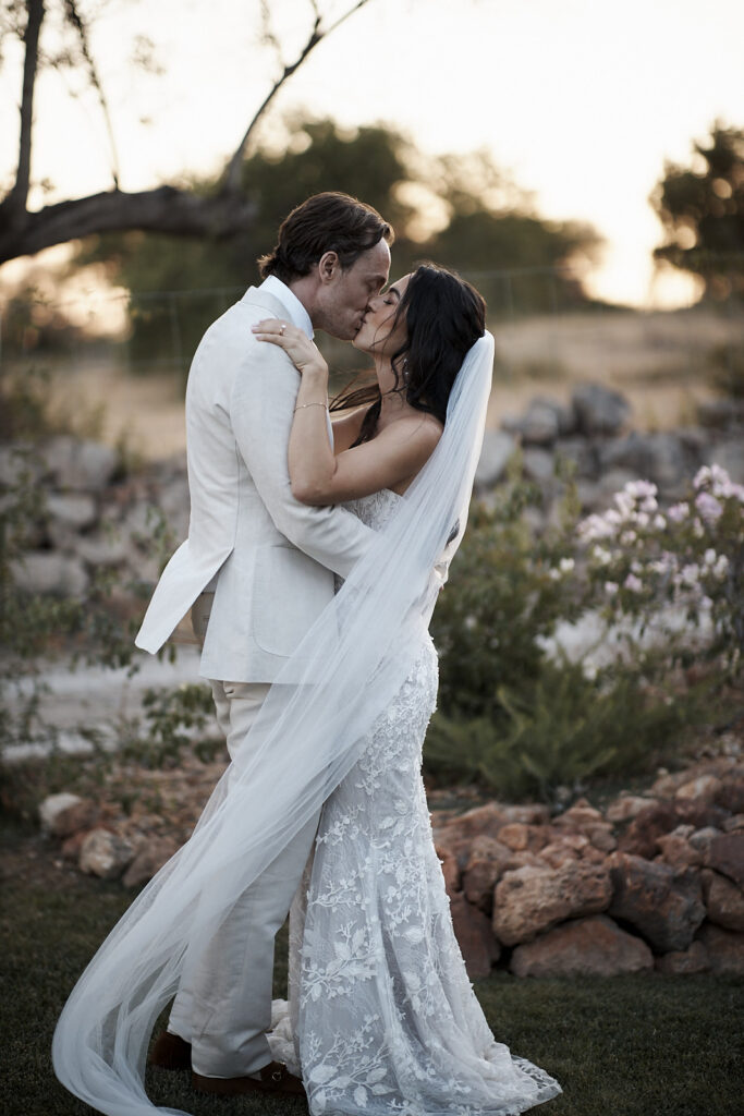 Braut und Bräutigam küssen sich im Abendlicht im Garten von Monte do Serrinho an der Algarve