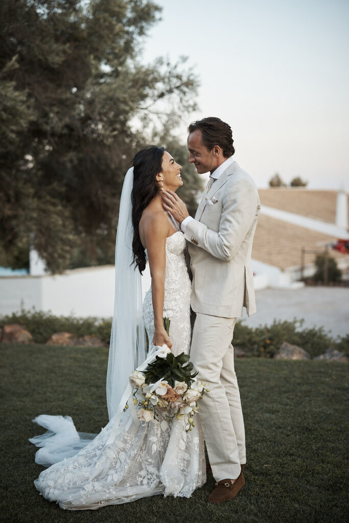 Braut und Bräutigam stehen sich mit Brautstrauß im Garten von Monte do Serrinho an der Algarve liebevoll gegenüber