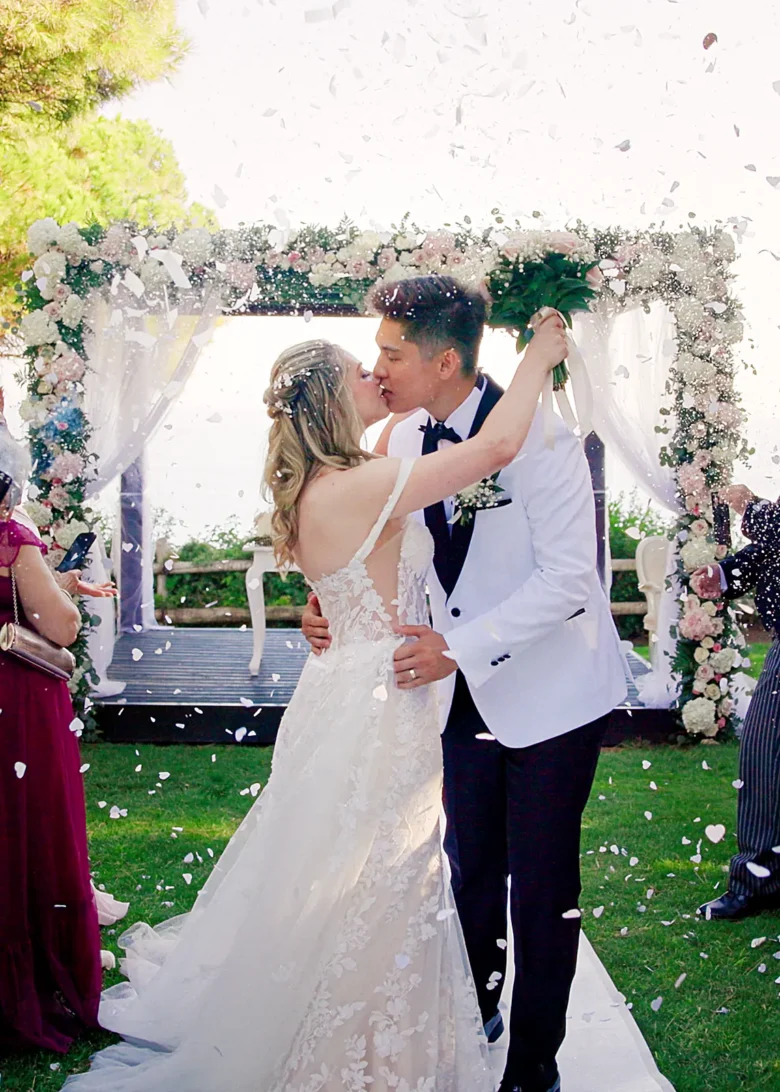 Bride and groom kissing after their ceremony at a Pine Cliffs wedding in the Algarve with confetti in the air